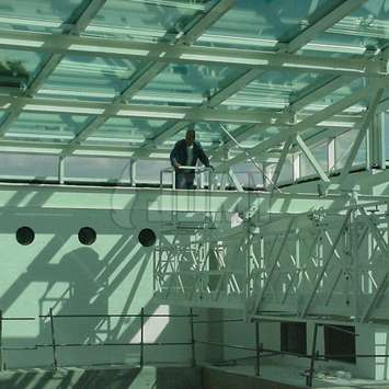 White mobile building maintenance unit with horizontal telescopic extension and worker on top. Mobile BMU with horizontal telescopic extension - Building Maintenance Unit